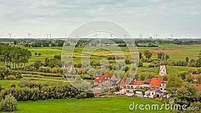 Flemish countryside with fields with trees, old houses and a windmill Editorial Stock Photo