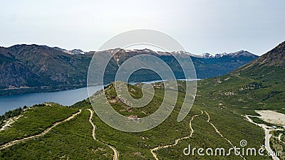 Aerial view of the green hill and mountainous lake surrounded by high mountain during summer time. Stock Photo