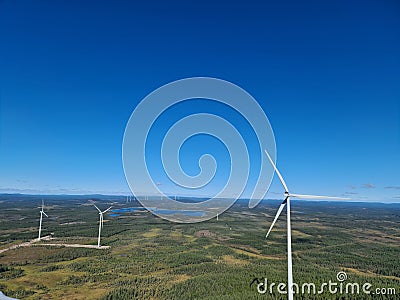 Aerial view of green valleys and hills with tall wind turbines under the clear blue sky Stock Photo