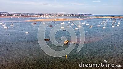 An aerial view of an harbor at low tide with sandy beach, boats, wreck and building area in the background under a majestic cloudy Stock Photo