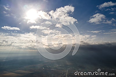 Aerial view from high altitude of distant city covered with puffy cumulus clouds forming before rainstorm in evening Stock Photo