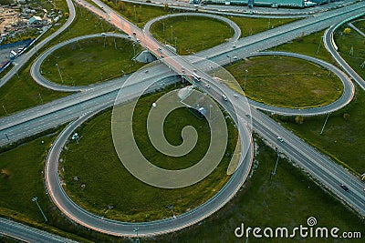 Aerial view at highway intersection or road junction with circle movement at sunset, cars and trucks traffic Stock Photo