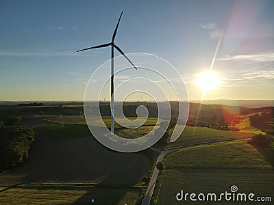 Aerial view of a landscape with agriculture fields, a road and a wind turbine on a sunny evening Stock Photo