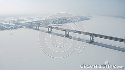 Aerial view of a long bridge above snow and ice covered river between two parts of a city. Clip. Winter landscape with a Stock Photo