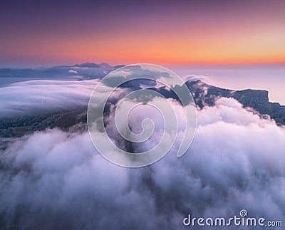 Aerial view of low clouds, mountains, sea and colorful sky at sunset. Stock Photo