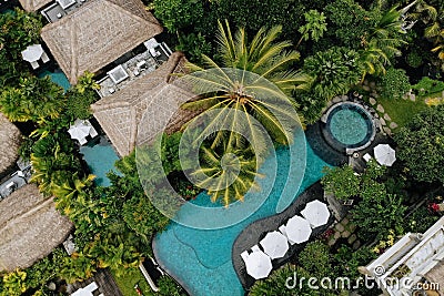 Aerial view of luxury hotel with straw roof villas and swimming pools in tropical jungle and palm trees. Luxurious villa Stock Photo