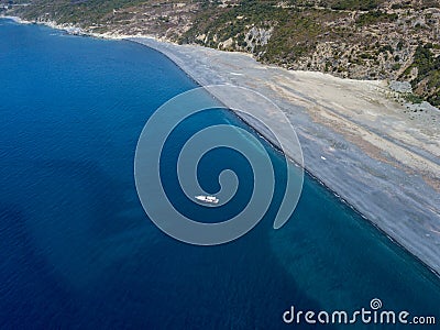 Aerial view of moored boat floating on a transparent sea. Nonza black beach. Corsica. France Stock Photo