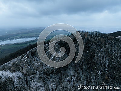 Aerial view of old ruins of fortress in the middle of winter forest. Drone view of snowy landscape with broken stone Stock Photo