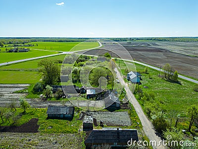 Aerial view over a small village near a dirt road. Large multi-colored fields planted with various agricultural crops. Wheat field Stock Photo