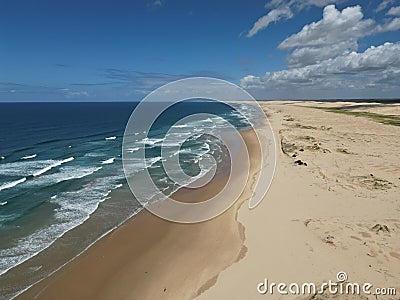 Aerial view of sandy beach with clear blue ocean and blue sky in the background Stock Photo