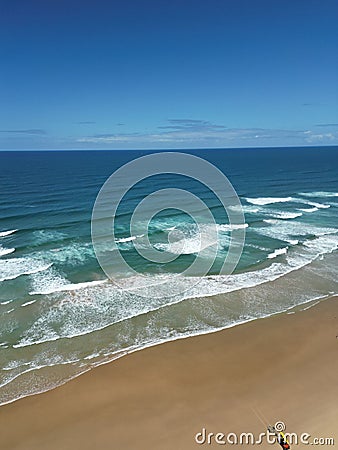 Aerial view of sandy beach with clear blue ocean and blue sky in the background Stock Photo