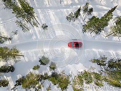 Aerial view of red car driving through the white snow winter forest on country road in Finland, Lapland Stock Photo