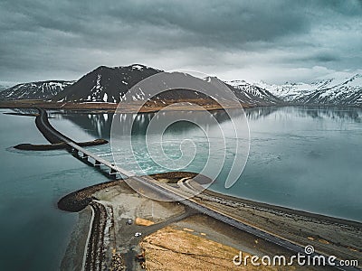 Aerial view of road 1 in iceland with bridge over the sea in Snaefellsnes peninsula with clouds, water and mountain in Stock Photo