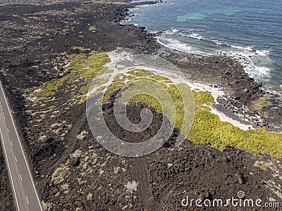 Aerial view of a road that runs through lava fields between the indented coastline of Lanzarote. Spain Stock Photo