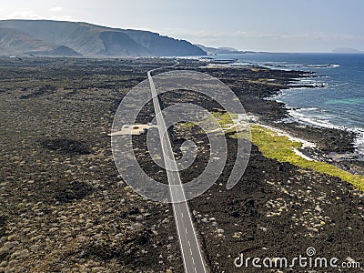 Aerial view of a road that runs through lava fields between the indented coastline of Lanzarote. Spain Stock Photo