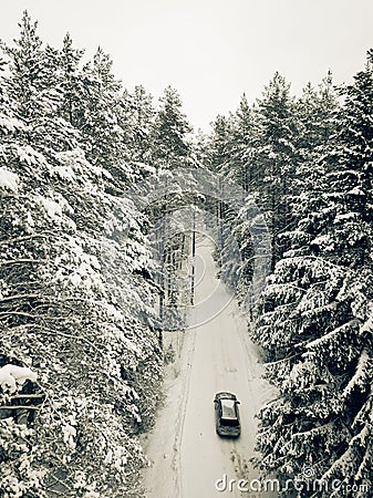 Aerial view on road in winter time, road surrounded with forest trees, car driving in winter time. Stock Photo
