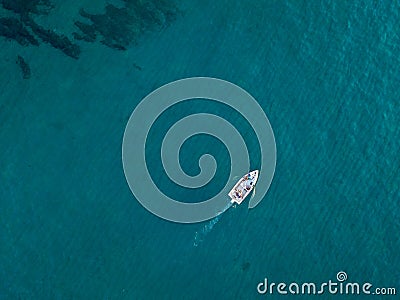 Aerial view of a rowing boat seen from above, powered by an engine. Blue sea that surrounds a boat that crosses it Stock Photo