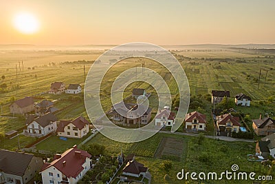 Aerial view of rural residential area with private homes between green fields at sunrise Stock Photo