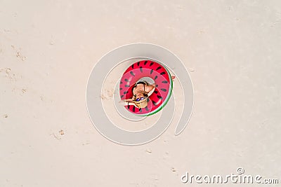 Aerial view of slim woman swimming on the swim ring donut in the transparent turquoise sea in Seychelles. Summer seascape with Stock Photo