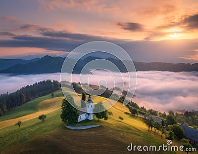 Aerial view of small church on the hill over pink low clouds Stock Photo