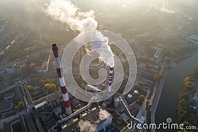 Aerial view of smoking chimneys of CHP plant and smog over the city and builidings in the background Stock Photo