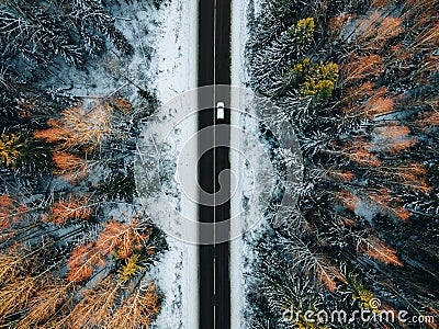 Aerial view of snow covered trees in forest and winter country road with a car Stock Photo