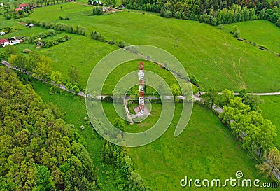 Aerial view on steel telecommunication tower in green land with meadow, forest and village Stock Photo