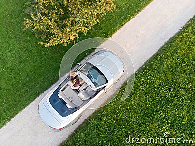 Aerial view of successful man driving and enjoying his silver convertible luxury sports car on the open country side Stock Photo