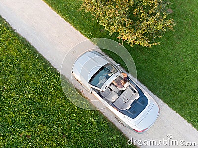 Aerial view of successful man driving and enjoying his silver convertible luxury sports car on the open country side Stock Photo