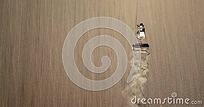 Aerial view the tractor is working in the field creating dust clouds. Spring work in the field. Photo from the drone Stock Photo