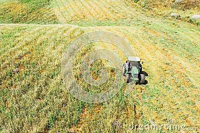 Aerial view, tractor mows grass for agriculture, livestock feed in the fields, meadows, hills Stock Photo