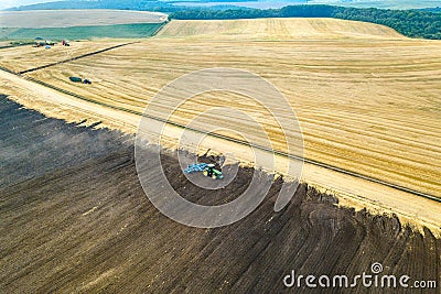 Aerial view of a tractor plowing black agriculture farm field after harvesting in late autumn Editorial Stock Photo