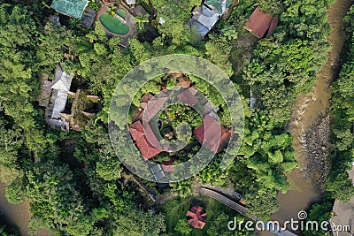 Aerial view of a tropical hotel or lodge located in the jungle and surrounded by lush green foliageand a small brown colored river Stock Photo