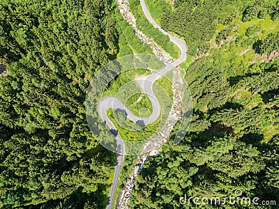 Aerial view of twisty road in the Alps with a small river and Bridge. Trees and road seen from top down. Strong green colors Stock Photo