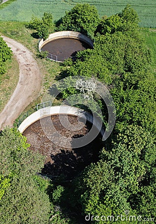 Aerial view of two open circular slurry tanks with trees growing at the edges Stock Photo