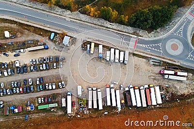 Aerial view of unpaved natural parking with lots of trucks, trailers and cars. Rest place near road and circle junction Stock Photo