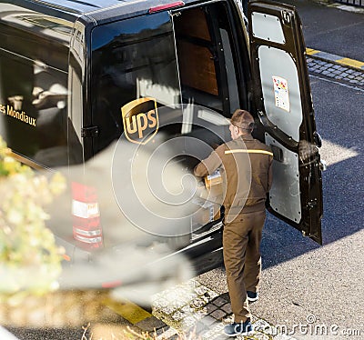 Aerial view of UPS driver in uniform next to his brown van loading unloading Editorial Stock Photo