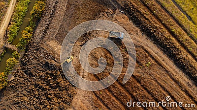 Aerial view of a wheel loader excavator with a backhoe loading sand onto a heavy earthmover at a construction site Stock Photo