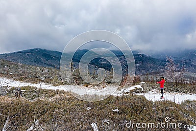 Aerial view on a woman runner in a red sweatshirt stands on a mountain trail ready to run. Stock Photo