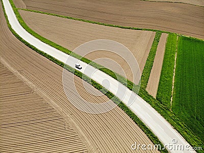 AERIAL: White car driving down a road winding through the scenic countryside. Stock Photo