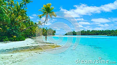 AERIAL: Young female tourist in bikini walking along the white sand shoreline. Stock Photo