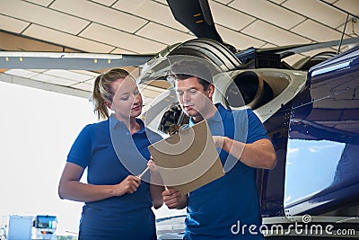 Aero Engineer And Apprentice Working On Helicopter In Hangar Loo Stock Photo
