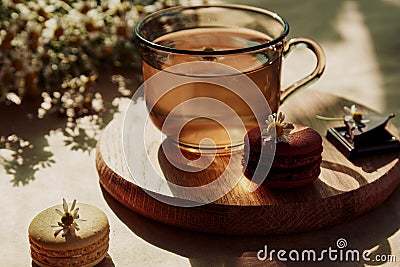 Aesthetic brunch of tea time, herbal tea and macarons dessert outside in the terrace under trendy hard shadows. Sweet Stock Photo