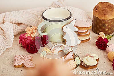 Aesthetic cozy Easter table with milk mug with glazed cookies, Cake and flowers. Springtime holiday floral background. Stock Photo