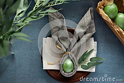 Aesthetic Easter table decoration, banny ears napkin and green dyed eggs on blue background, spring holiday mockup with copy space Stock Photo