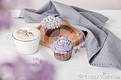 Aesthetic french dessert - cupcakes and coffee cup among lilac flowers. Guilty pleasure Stock Photo