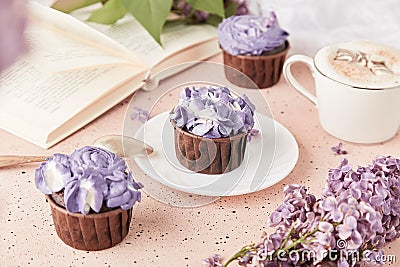 Aesthetic french purple floral cupcakes using trend Dreamy Escapism. Coffee time among lilac flowers, reading the book Stock Photo