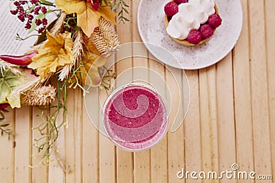 Aesthetic french raspberry tart with healthy pink strawberry smoothie on the wooden table among autumn decorations Stock Photo