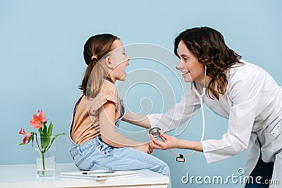 Affable female doctor examining tonsils of a happy little girl. Side view Stock Photo