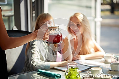 Affable waiter of cafe give sweet beverages for two beautiful female clients Stock Photo